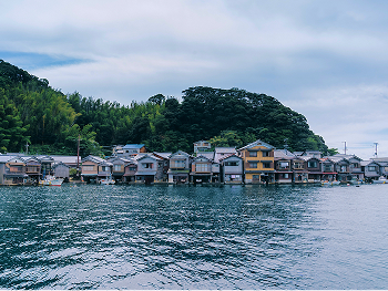 A scenic view of Ine, a coastal town lined with traditional boathouses along the shore.