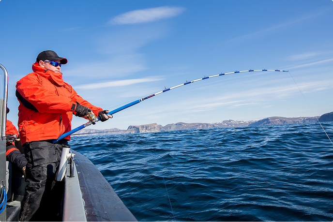 A man enjoying serious lure fishing from a boat against the backdrop of the beautiful coastline and blue sky of Ine.